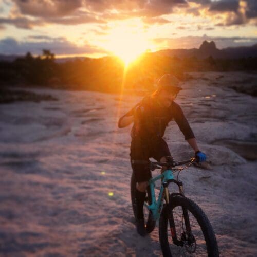 Brian Bergeler riding his mountainbike with the sun setting behind him