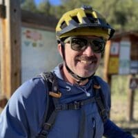 Travis Hochard outside with his bike helmet and backpack on